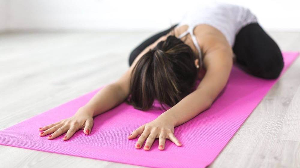 Imagen de una mujer haciendo estiramientos de yoga en casa
